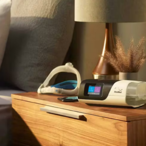 Autocpap Airsense 11 e máscara Resmed sobre uma mesa de cabeceira em um ambiente que transmite tranquilidade no meio da tarde.