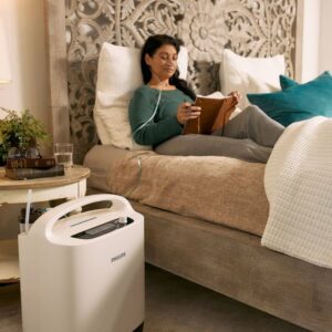 Mujer en la cama leyendo mientras usa el kit de oxígeno de philips Oxygenate 5